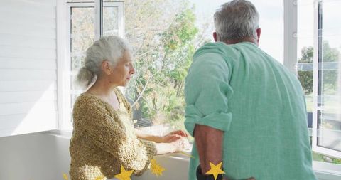 Sunlit Senior Couple Conversing at Open Casement Window in Cozy Garden Sunroom
