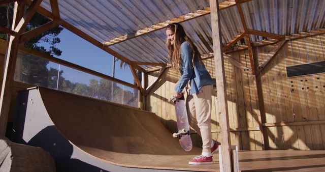 Image of happy caucasian female skateboarder training in skate park. Skateboarding, sport, active lifestyle and hobby concept.