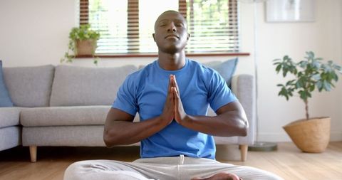 Man meditating cross-legged in tranquil living room setting