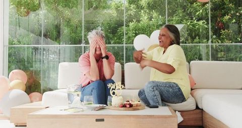 Joyful senior lesbian couple celebrating birthday at home