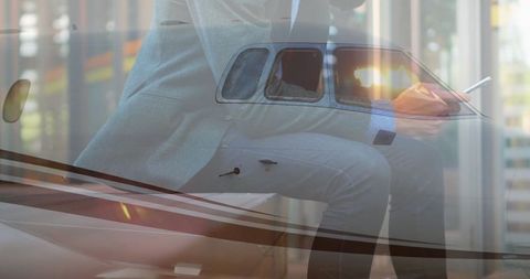 Executive with smartphone beside private jet wing