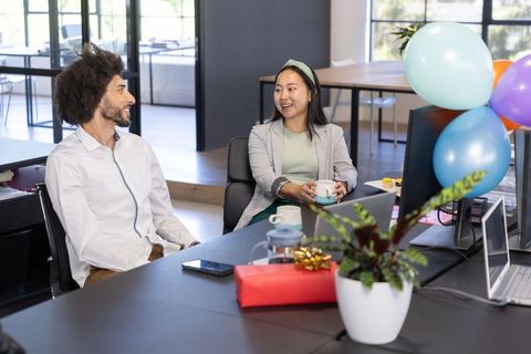 Coworkers Celebrating in Modern Office with Balloons and Coffee