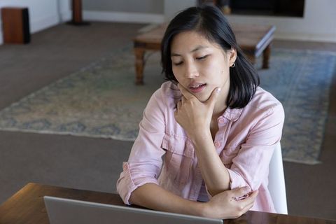 Asian Woman in Light Pink Shirt Working at Home with Laptop