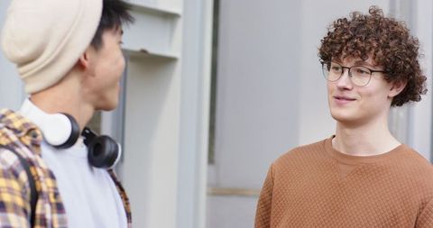 Diverse college friends chatting outdoors on campus casual conversation with headphones