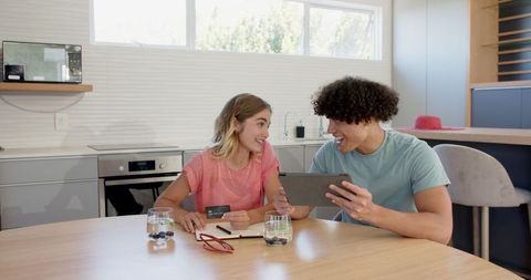 Young Couple Shopping Online at Kitchen Table Using Tablet
