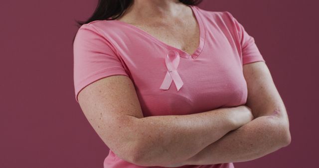 Woman with arms crossed wearing pink breast cancer awareness ribbon on t-shirt. symbol of breast cancer awareness.