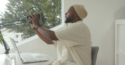 African american creator adjusting microphone for podcast recording in sunlit workspace