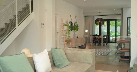Greige sectional anchoring modern open-plan living and dining room with sage pillows and plants