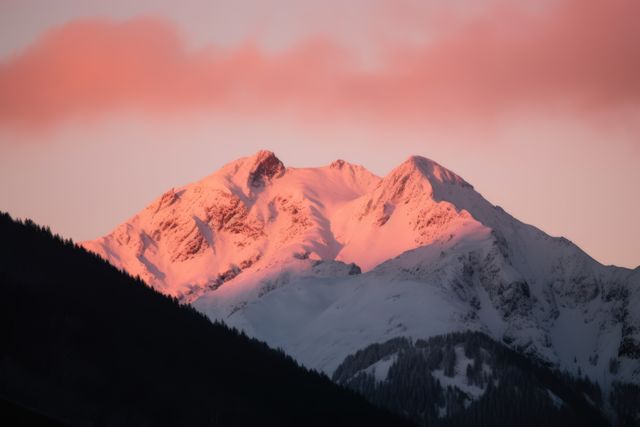 Alpenglow bathes a snowy mountain peak at dusk. Capturing nature's serene beauty, the scene inspires awe and tranquility.