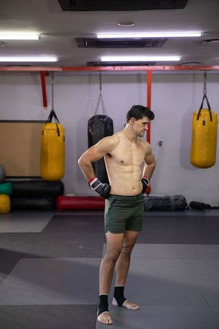 Shirtless mma fighter standing in gym after training looking focused and determined