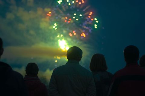 Silhouetted people watching vibrant fireworks display
