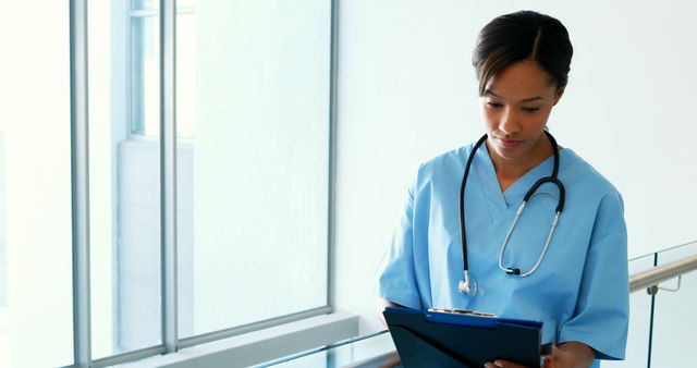 Nurse in Scrubs with Stethoscope Holding Clipboard in Hospital Corridor - Download Free Stock Images Pikwizard.com