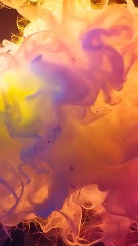 Vertical macro video of billowing pigment plume in water with filaments and warm backlight