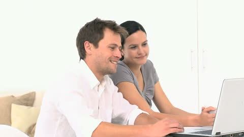 Young Couple Smiling While Browsing Laptop