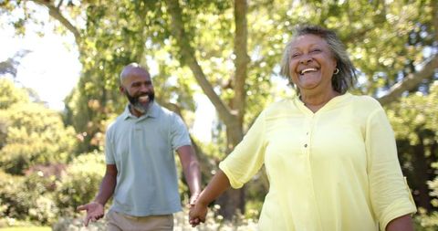 Joyful Senior Couple Walking Hand in Hand in Sunlit Park