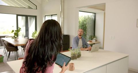 Young multicultural couple using smart home technology in modern kitchen