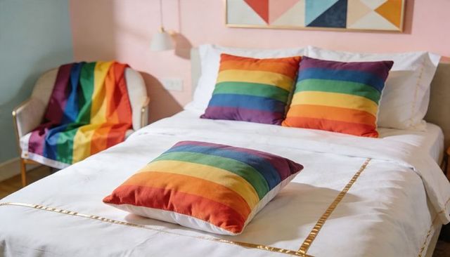 Rainbow-striped pillows on white bed with gold-trim bedding in pastel boutique bedroom