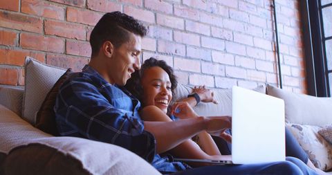 Young Couple Relaxing on Couch Browsing Internet Together