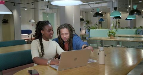 African American colleagues collaborating on laptop in modern open-plan coworking space