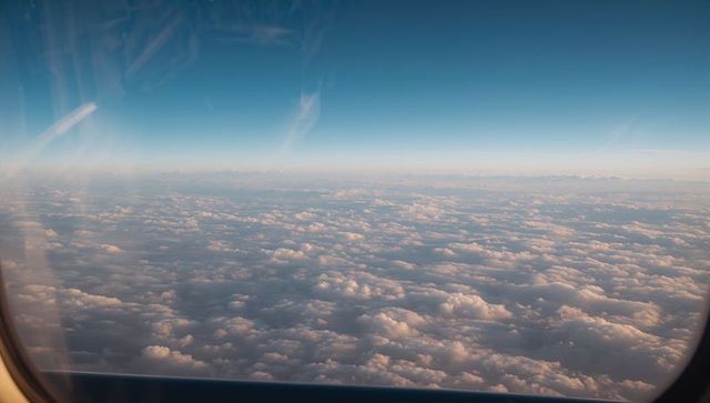 Viewing Sunlit Cloudscape through Airplane Window at Cruising Altitude