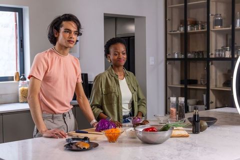 Multiracial coworkers preparing meal at marble kitchen island with ring light