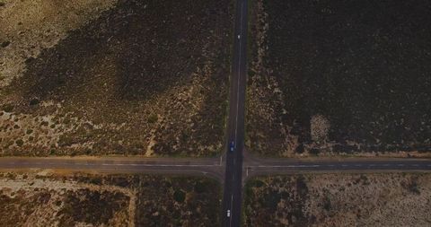 Aerial intersection crossing with truck and car on arid plain two-lane highway