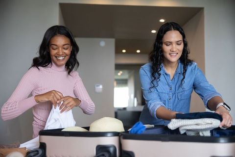 Female Friends Packing Suitcases for Travel Adventure at Home