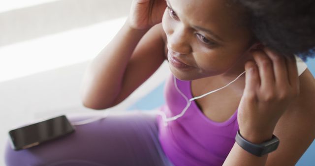 Happy african american wearing sportswear and earphones, exercising. domestic lifestyle, spending free time at home.
