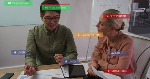 Colleagues collaborating over tablet reviewing charts with social notification overlays