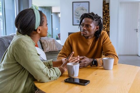 African american couple having serious conversation at home over coffee, tense discussion