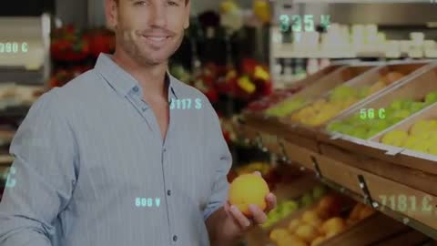 Man holding orange in supermarket with augmented reality overlay showing prices and ripeness