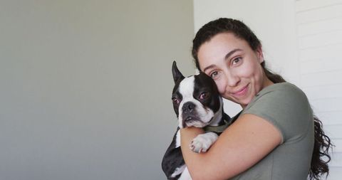 Smiling Woman Hugging Adorable Boston Terrier Dog Indoors