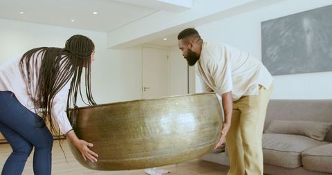 Interracial Family Tidying Living Room by Moving Coffee Table