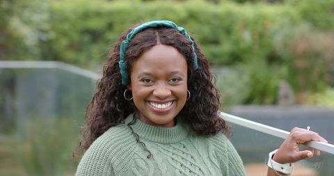 Confident African-American woman smiling outdoors in green knit sweater and headband