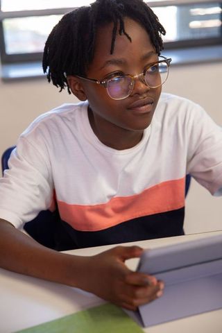 African American Teen Student Using Tablet in Bright Classroom