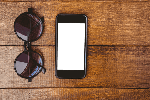 Transparent phone and sunglasses on rustic wooden surface