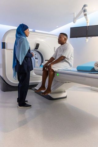 Radiology nurse in hijab consulting african american patient before ct scan in modern clinic