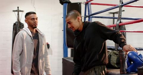 Boxing training partners preparing for sparring at gym ring grabbing gloves and water