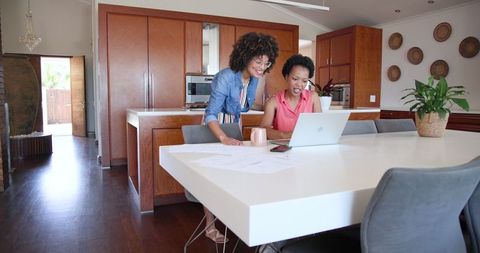 Diverse Couple Celebrating Achievement with Laptop in Home Office