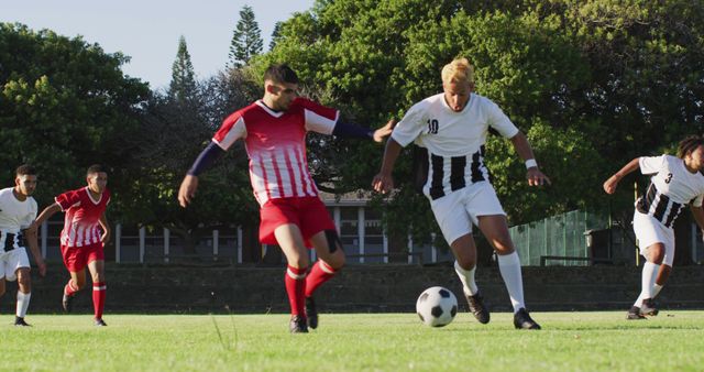 Soccer players from opposing teams dressed in red and white uniforms competing on a green field. Suitable for illustrating sports events, advertising athletic gear, promoting team activities, or sports-related content.