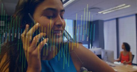 Smiling professional woman talking on phone with analytics charts overlay in office