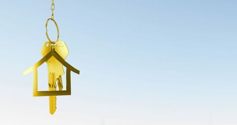 Golden house key suspended against clear blue sky