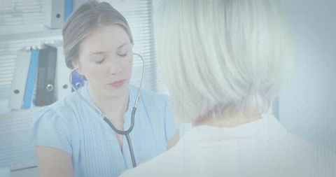 Clinician listening to senior patient with stethoscope during routine checkup in medical office