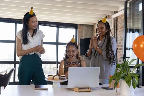 Diverse Team Celebrating Birthday at Office with Laptops and Cupcakes