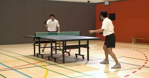 Competitive Game of Table Tennis in Indoor Gymnasium