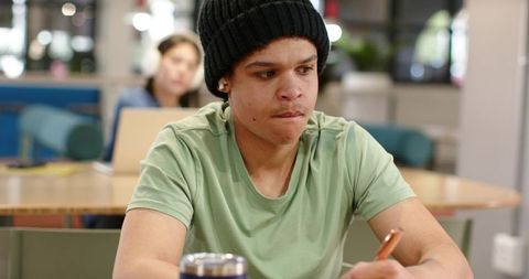 African american student concentrating while studying in campus lounge with notebook