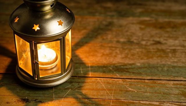 Metal lantern casting warm amber glow on weathered wooden surface
