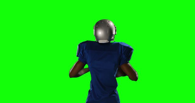 This image depicts the back of an American football player facing a green screen. The football player is wearing a helmet and sports uniform, including football pads under the jersey. This type of image is ideal for creating promotional materials, educational tutorials, and digital edits requiring customizable backgrounds.