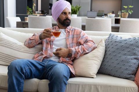 Man in Traditional Turban Relaxing with Tea on Modern Sofa