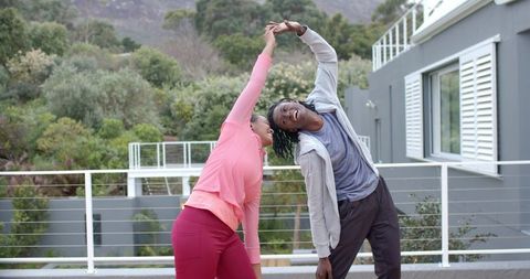 African American Couple Stretching Together on Balcony Deck in Activewear